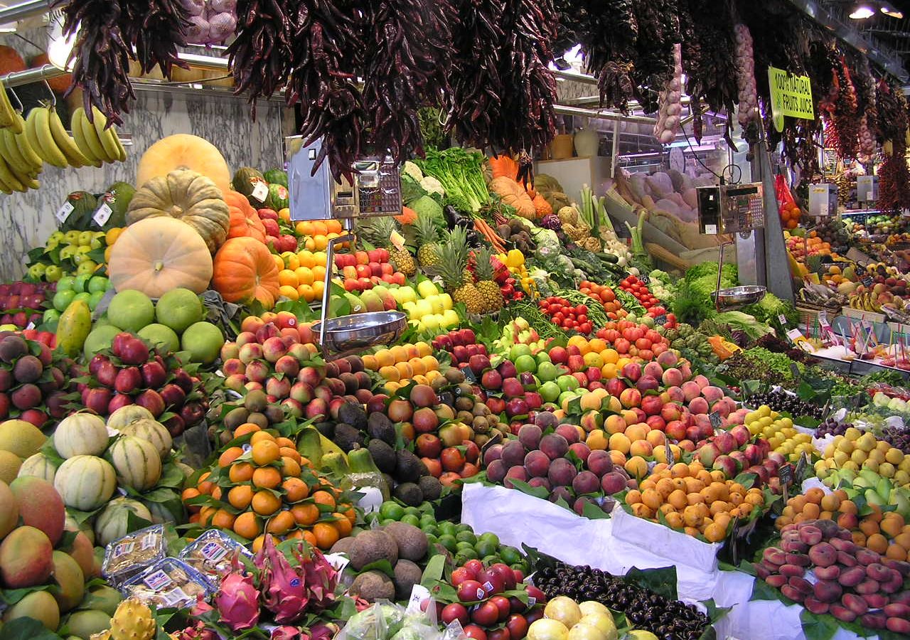 Fresh produce and fruit stalls inside La Boqueria market in Barcelona, a top stop for where to eat in Barcelona