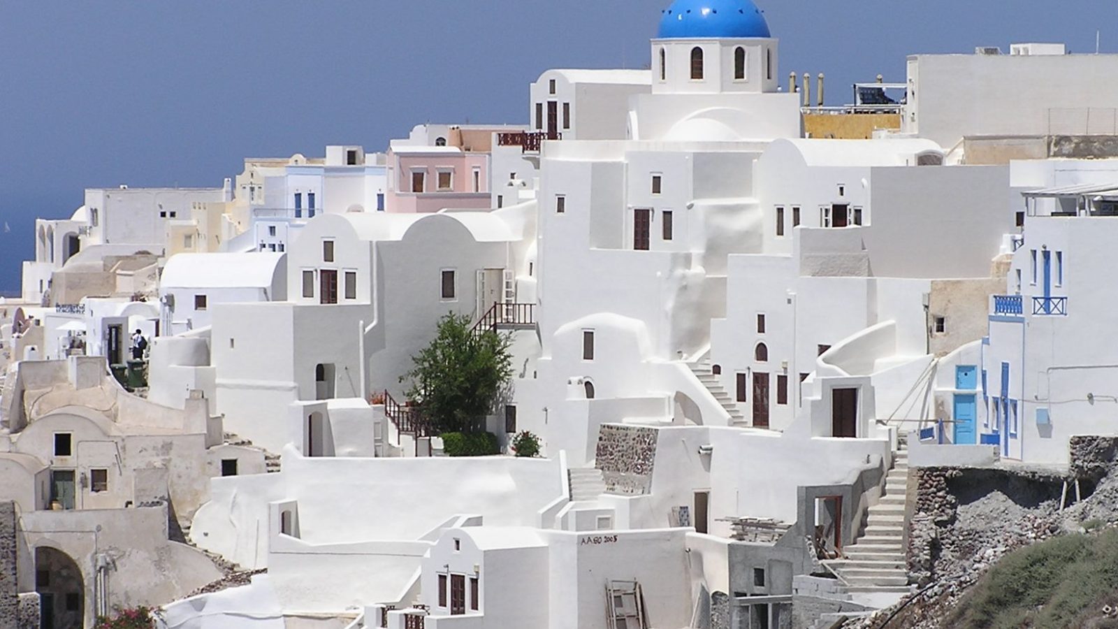 Whitewashed buildings and blue-domed church in Oia, Santorini at sunset, the classic image travelers picture from this Santorini travel guide