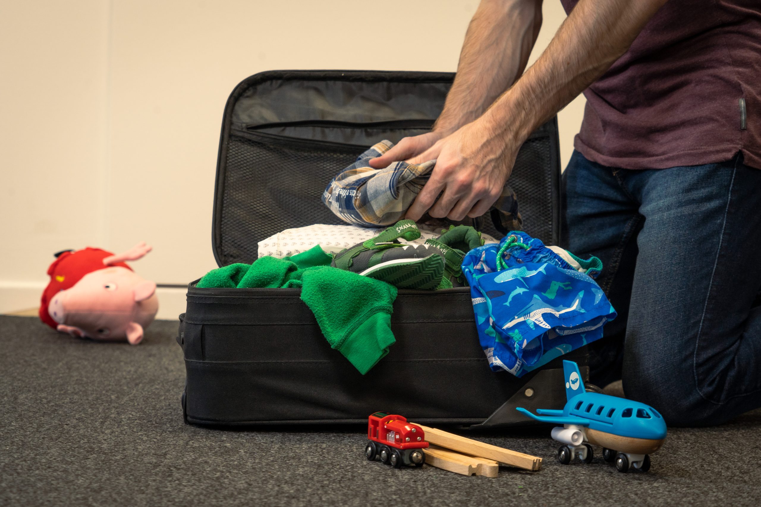 Traveler packing a suitcase for cold-weather travel with warm layers laid out