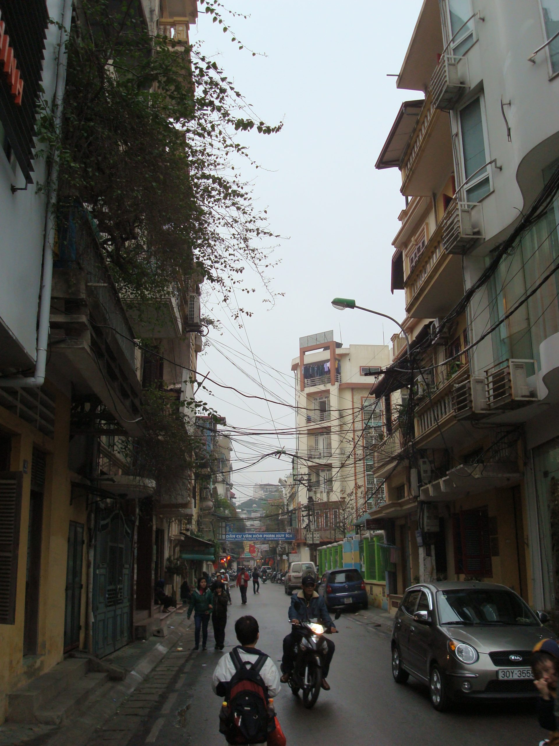 Narrow street view through Hanoi's Old Quarter lined with shops and stalls