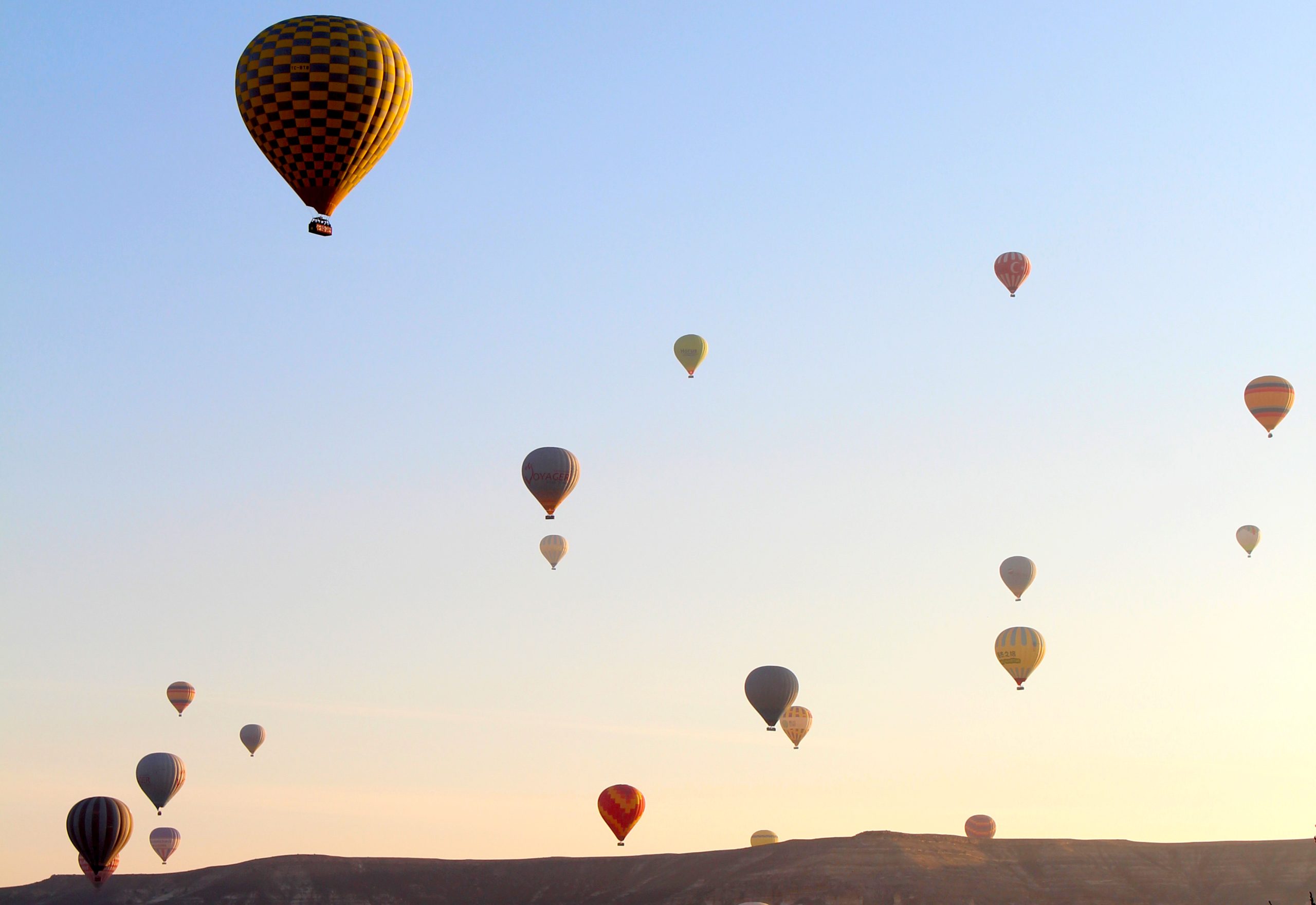 Hot air balloons over Cappadocia cave hotel valley at sunrise