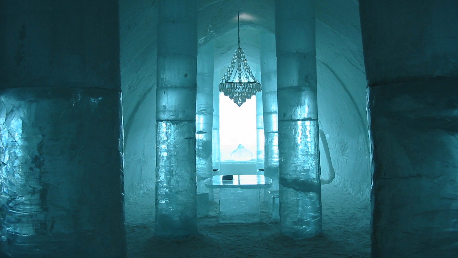 Carved ice hotel suite in Scandinavia with sculpted ice furniture and reindeer hides
