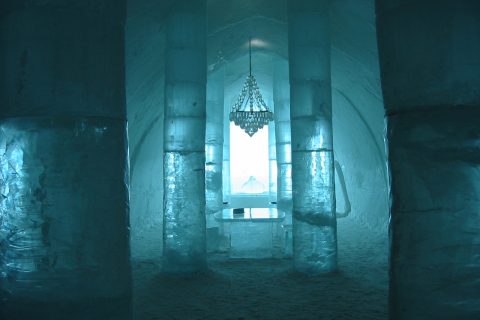 Carved ice hotel suite in Scandinavia with sculpted ice furniture and reindeer hides