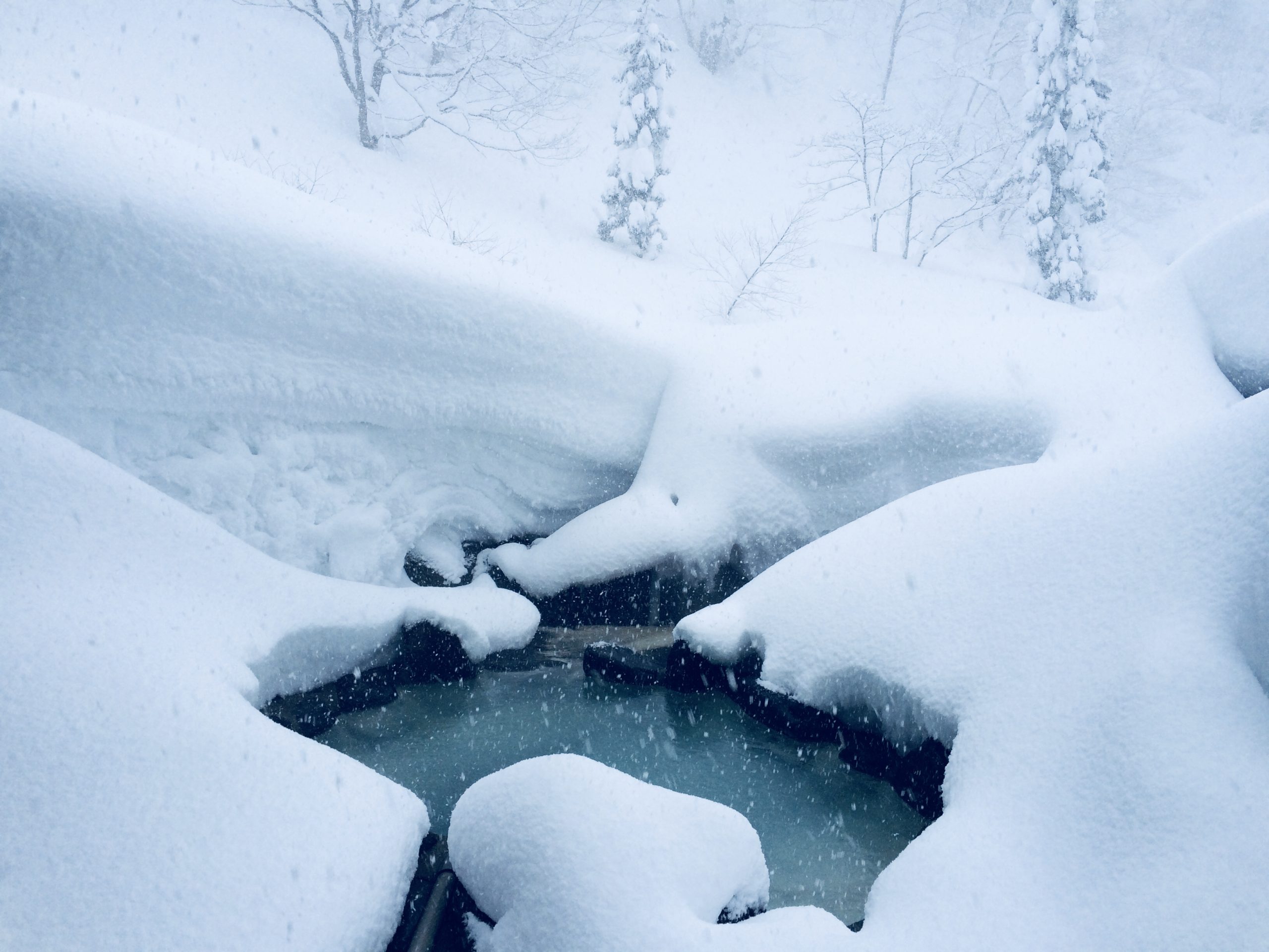 Snow-covered outdoor onsen bath at a Japanese hot spring resort in winter