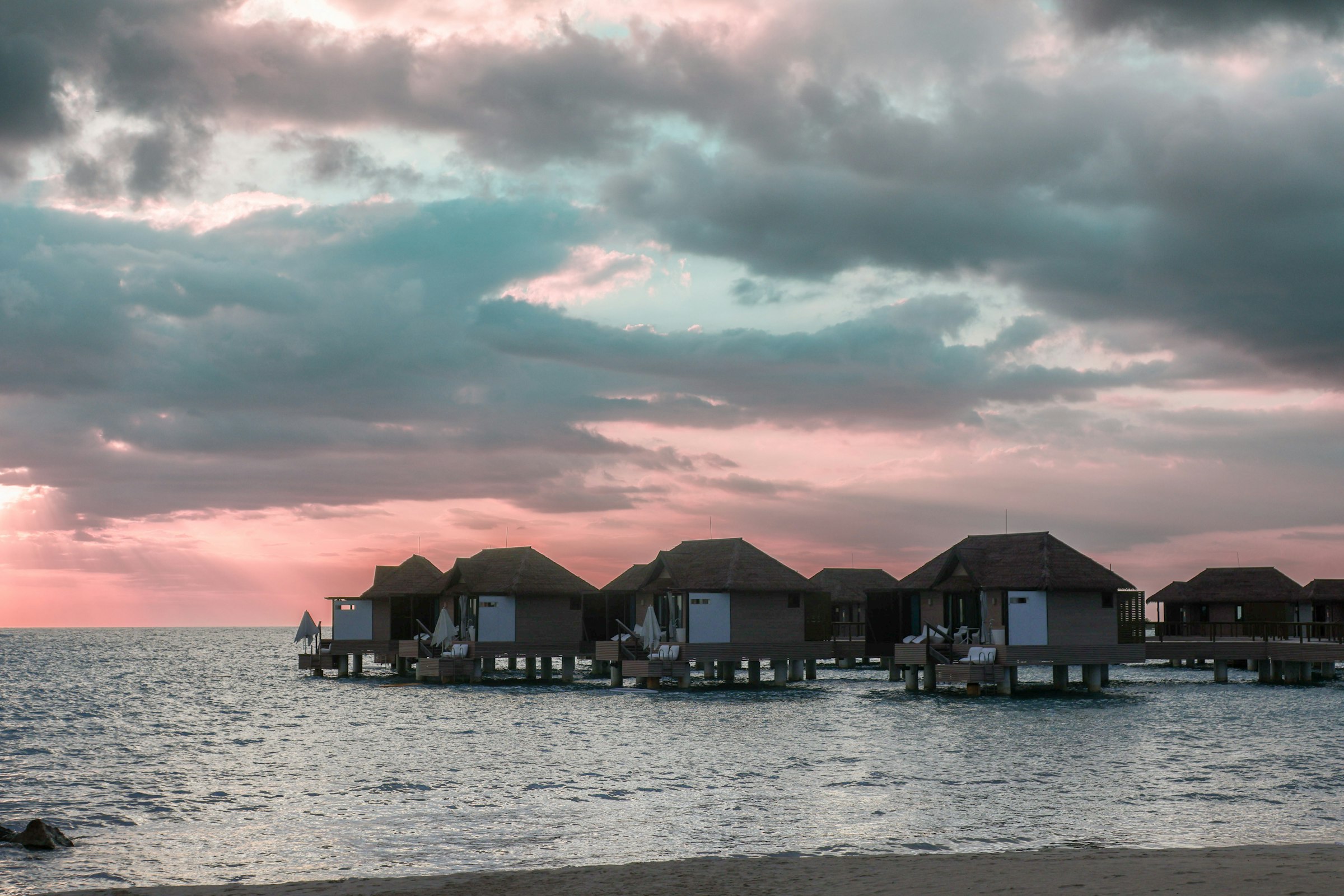 Overwater bungalow resorts lined up over shallow Caribbean water in Jamaica