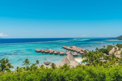 Overwater bungalow resorts over turquoise lagoon water in Moorea