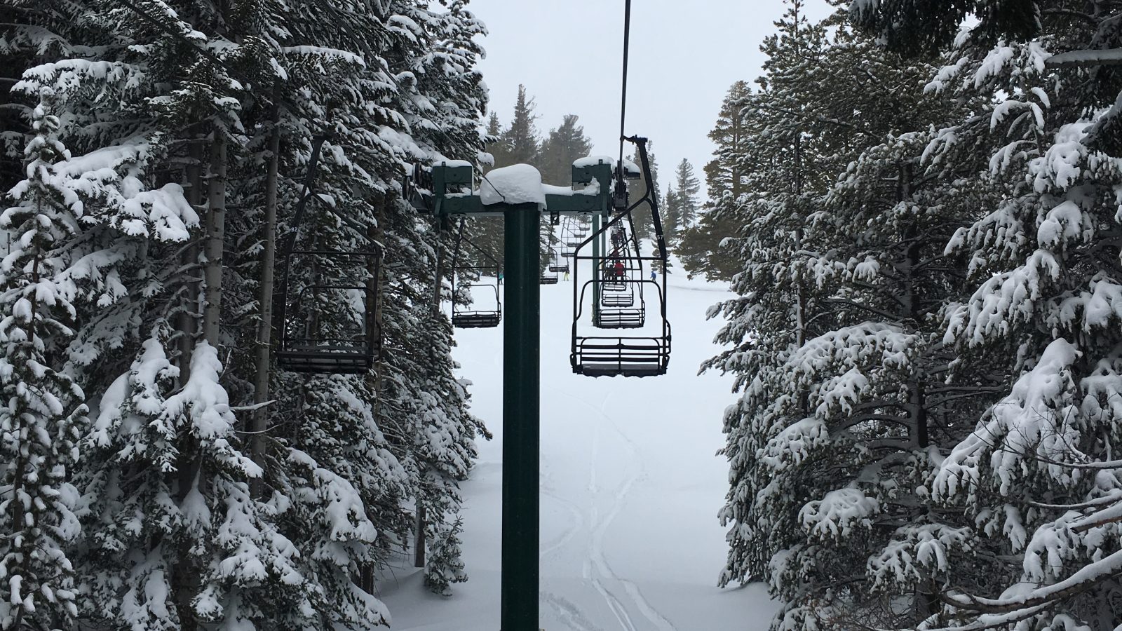 Ski trip packing list scene of a chairlift carrying skiers up a snowy mountain