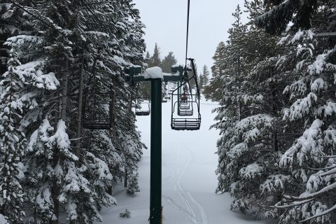 Ski trip packing list scene of a chairlift carrying skiers up a snowy mountain