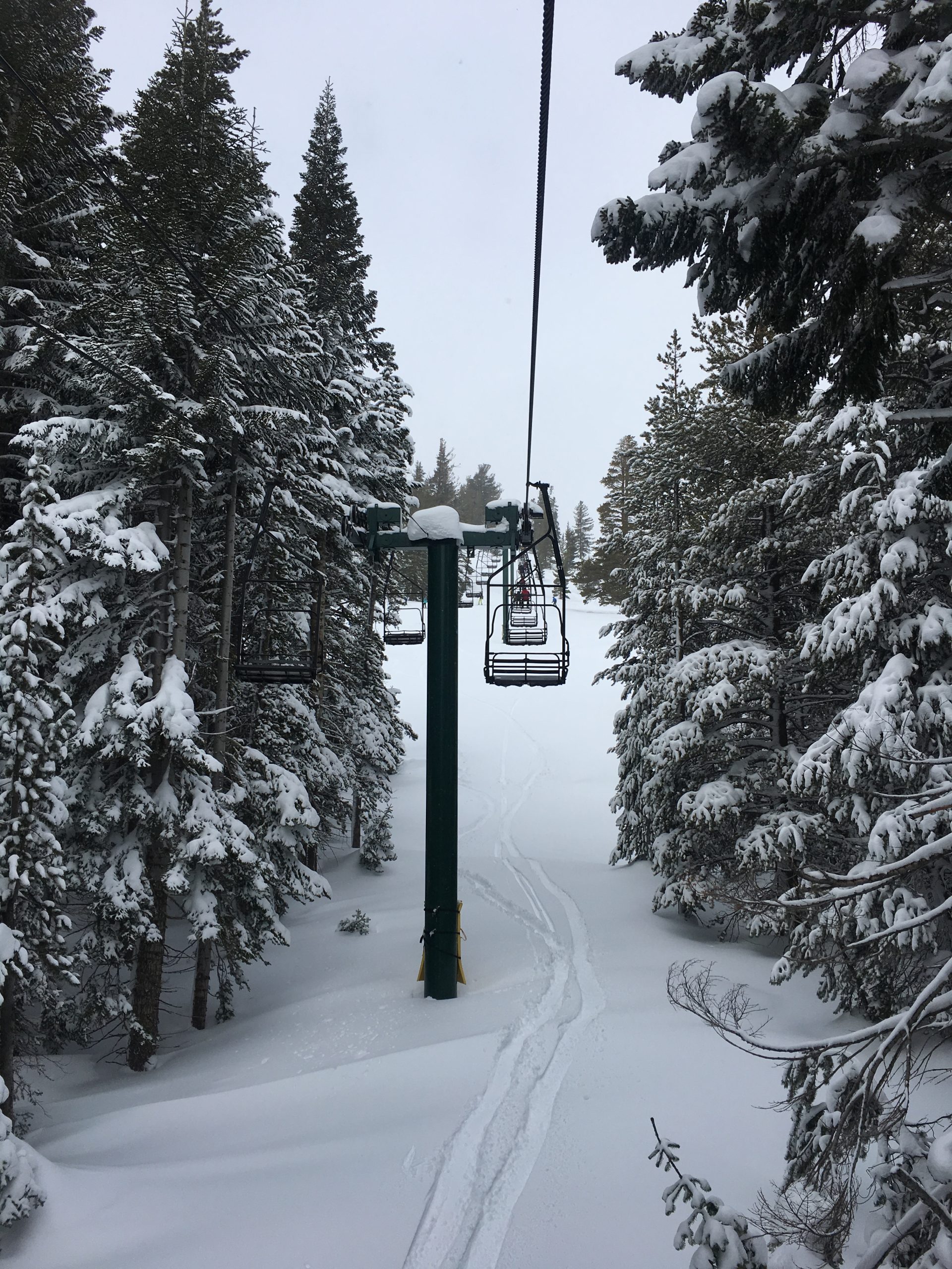 Ski trip packing list scene of a chairlift carrying skiers up a snowy mountain