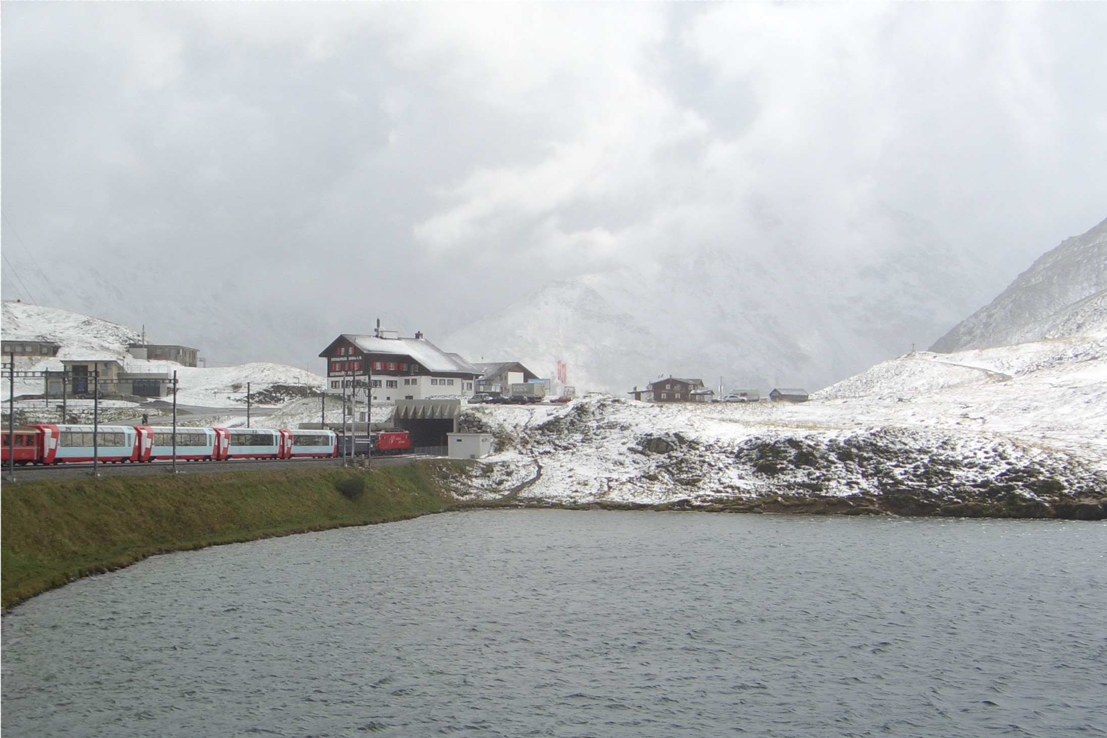 Panoramic train carriage passing Oberalpsee lake, an example of scenic slow train travel in Europe