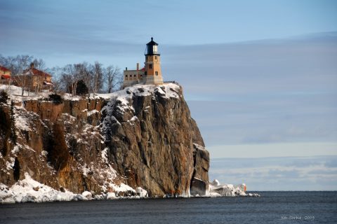 A historic lighthouse hotel-style tower perched on a cliff above Lake Superior